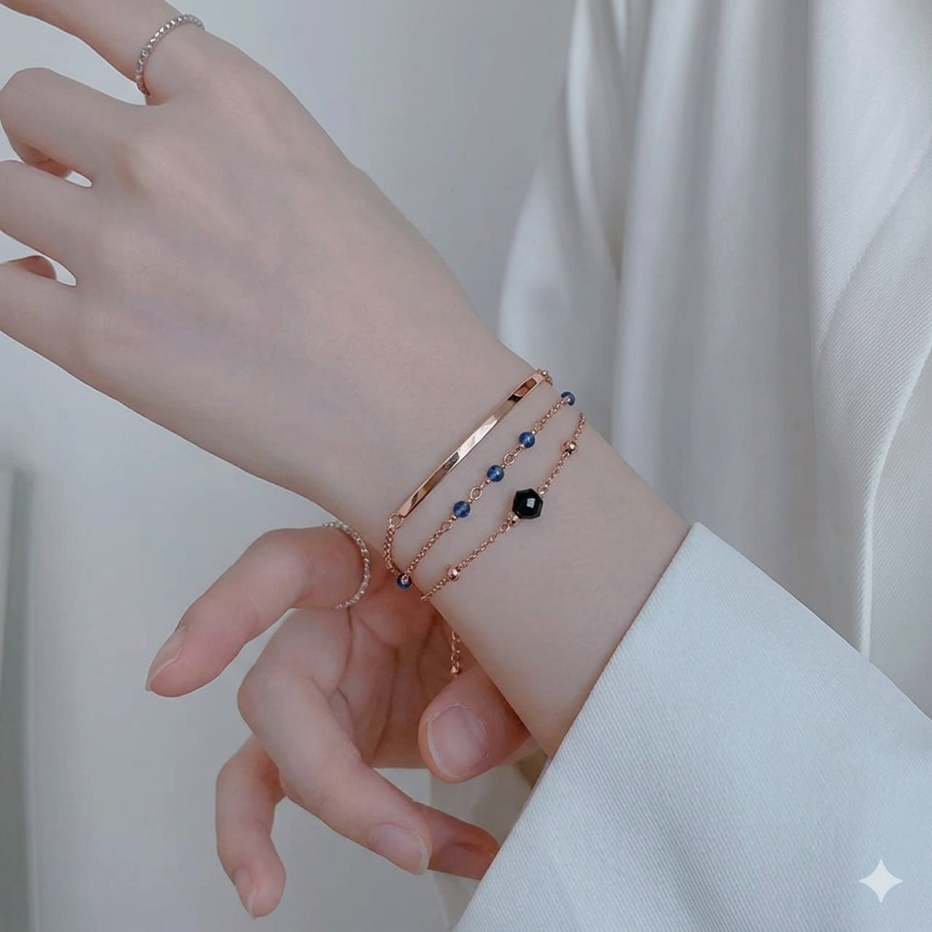 A close-up shot of a hand wearing a rose gold bracelet and bangle set.